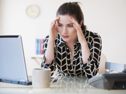 Caucasian businesswoman with headache using laptop