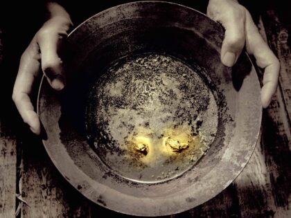 Man holding pan containing nuggets of gold, close-up (tinted B&W) - stock photo