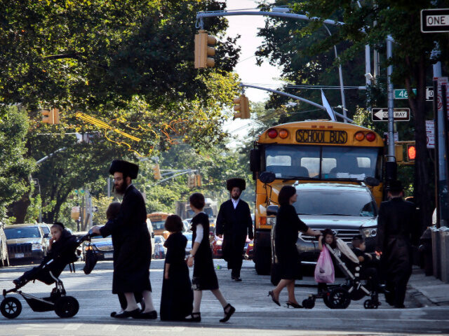 Children and adults cross a street in front of a school bus in Borough Park, a neighborhoo