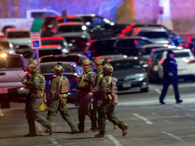 Law enforcement agents walk in the parking lot of a shopping mall, Wednesday, Feb. 15, 202