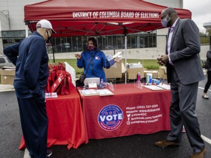 WASHINGTON, DC - October 13: Board of Elections staffer LaVonna McCann, center, talks to local basketball greats Phil Chenier, left, and Harvey Grant, right, at a District voter registration event at the Mystics Sports arena, in Washington, DC on October 13. (Bill O'Leary/The Washington Post via Getty Images)