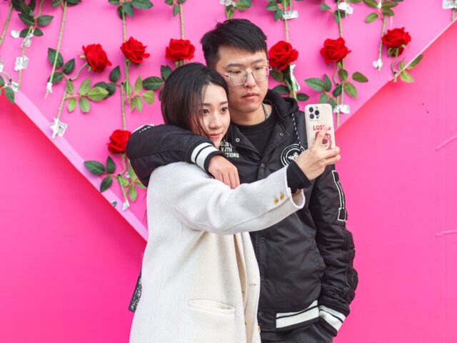 NANCHANG, CHINA - FEBRUARY 14: A couple take a selfie in front of a wall of red roses outs