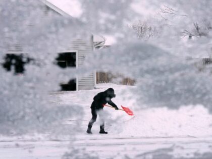 A local resident shovels snow off the end of a driveway, Thursday, Dec. 22, 2022, in Urban
