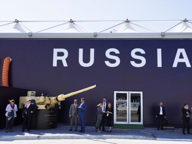 Russian salespeople stand by a tent for Russian weapons manufacturers at the International