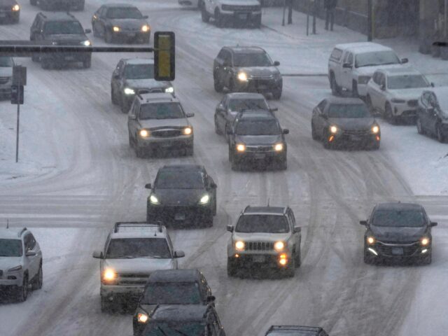 Vehicles drive in downtown Minneapolis as snow falls, Tuesday, Feb. 21, 2023. A winter sto
