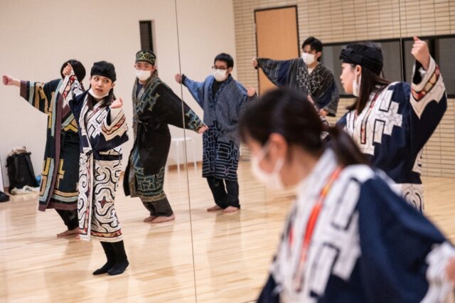 Indigenous student Mizuki Orita (2nd L) practices a traditional dance with members of the