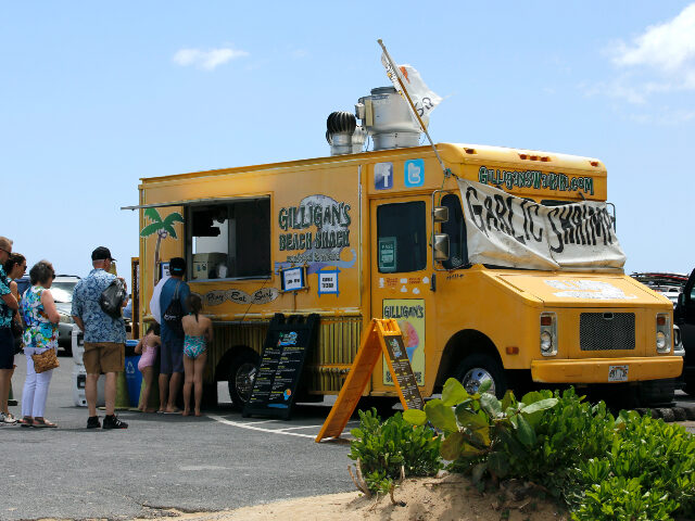 People line up at a food truck parked near Waikiki Beach in Honolulu, Monday, May 23, 2022