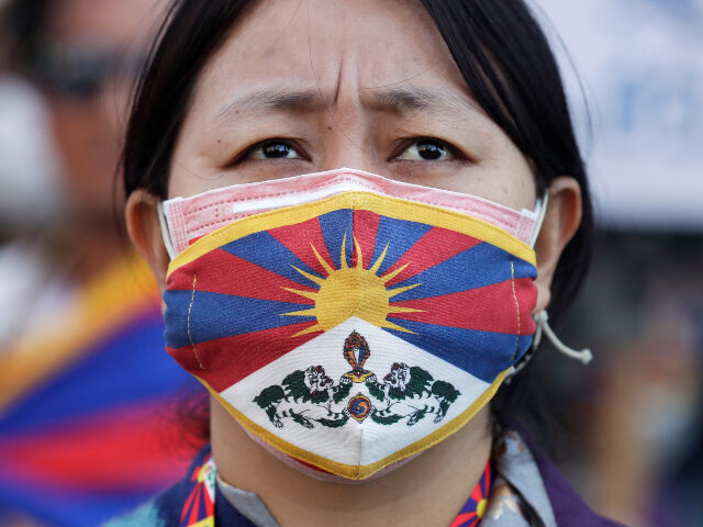 A Tibetan woman wears a face mask featuring the Tibetan national flag during a march in Ta