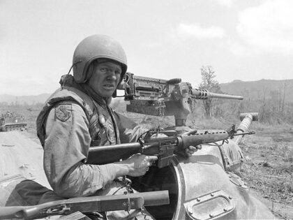 An American soldier struggles with a 50-cal. machine gun atop a tank, turns to using an M-16 rifle elsewhere in Indochina, North Vietnamese on Sunday, March 29, 1971 attacked a base south of Danang. (AP Photo/Neal Ulevich)