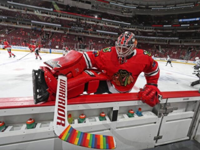 CHICAGO, ILLINOIS - APRIL 12: Goalie Collin Delia #60 of the Chicago Blackhawks warms up with rainbow tape on his hockey stick in honor of Pride Night, prior to the game against the Los Angeles Kings at United Center on April 12, 2022 in Chicago, Illinois. (Photo by Chase Agnello-Dean/NHLI …