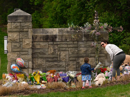 A woman and child bring flowers to lay at the entry to Covenant School which has becomes a memorial for shooting victims, Tuesday, March 28, 2023, in Nashville, Tenn. (AP Photo/John Amis)