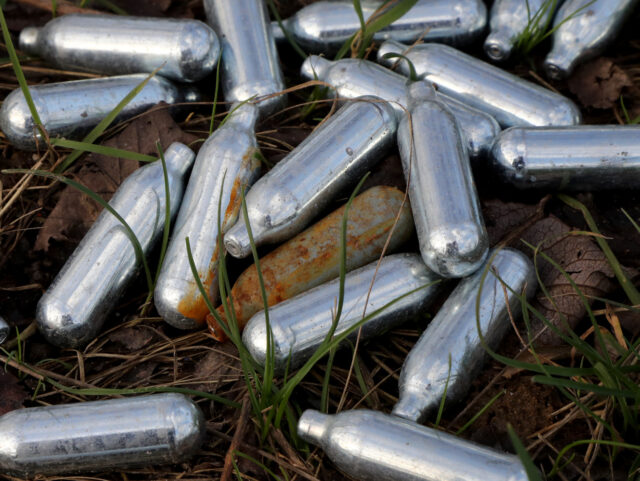 A view of canisters of nitrous oxide, or laughing gas, discarded by the side of a road nea