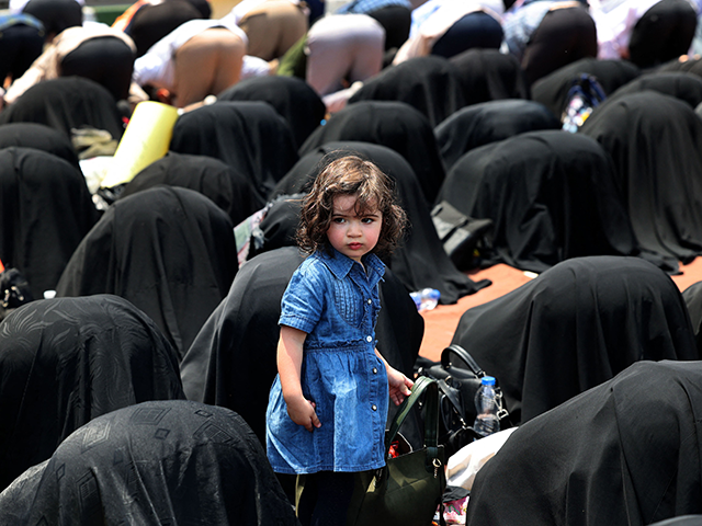 A girl looks on as Iranians pray during a protest to condemn the ongoing Israeli air campa
