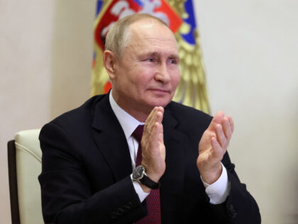 Russian President Vladimir Putin applauses as he attends an online conference in his resid