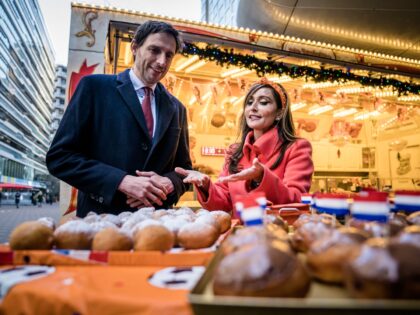 Dutch Minister of Foreign Affairs Wopke Hoekstra (L) and US ambassador Shefali Razdan Duggal stand in front of an oliebollen (doughnut balls) stall at The Hague Central Station, in The Hague, on December 7, 2022. - Duggal hands out oliebollen after she lost a bet with the Dutch ambassador to …