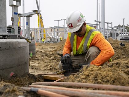 A worker splices copper cables while building the grounding grid at the onshore substation