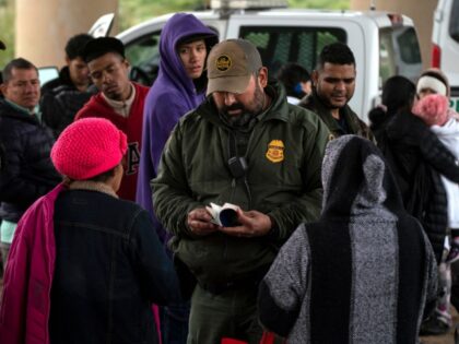A Border Patrol agent checks an asylum seeker's passport after she turned herself in,
