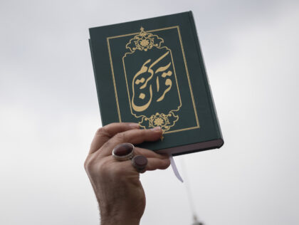 An Iranian cleric holds up a copy of Muslims holy book of Koran while taking part a protes