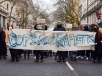 LONDON, UNITED KINGDOM - 2023/02/18: Protesters march with a banner which states 'Cops are rapists' during the demonstration. Protesters gathered outside New Scotland Yard and marched to Charing Cross Police Station in protest against sexual violence and violence by police officers such as David Carrick, Wayne Couzens and other officers, …