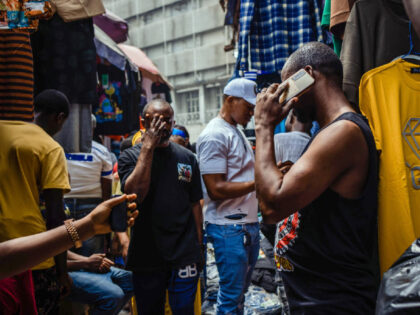 A vendor talks on a smartphone inside a market on Broad Street in Lagos, Nigeria, on Monda