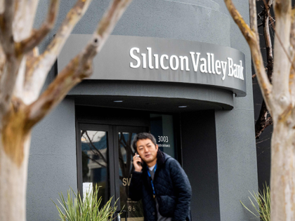A pedestrian speaks on a mobile telephone as he walks past Silicon Valley Banks headquarters in Santa Clara, California on March 10, 2023. - US authorities swooped in and seized the assets of SVB, a key lender to US startups since the 1980s, after a run on deposits made it …