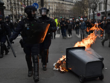PARIS, FRANCE - MARCH 23: Riot police walk past a garbage set on fire by demonstrators during a protest against the government after pushing the pensions reform without a vote using article 49.3 of the constitution, and surviving a no-confidence motion at the parliament, in Paris, France on March 23, …