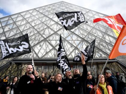 TOPSHOT - Employees hold banners and unions' flags as they block the entrance of the Musee du Louvre to denounce government's controversial pension reform, in Paris, on March 27, 2023. - A spokeswoman for the Parisian museum told AFP that this blocking of entries was carried out "by employees of …