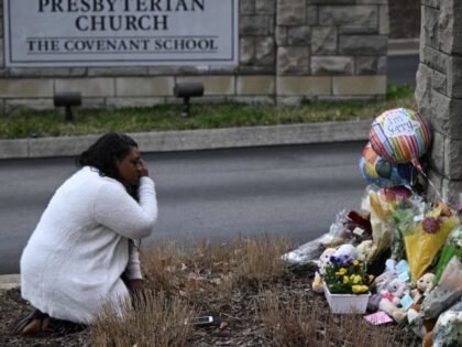 A woman pays her respects at a makeshift memorial for victims outside the Covenant School building at the Covenant Presbyterian Church following a shooting, in Nashville, Tennessee, on March 28, 2023. - A heavily armed former student killed three young children and three staff in what appeared to be a …