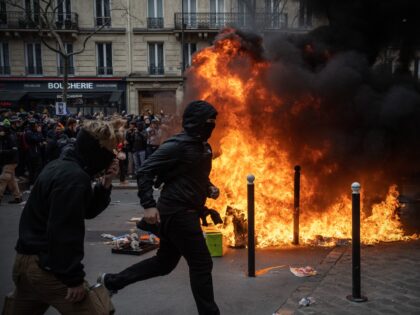 PARIS, FRANCE - MARCH 28: Protesters run past a fire during a rally against pension reform