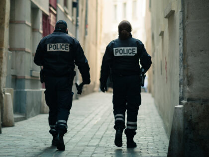 Paris, France - April 2012: A pair of police officers with the word "POLICE" written on the back of their jackets walk through a historic back alley.