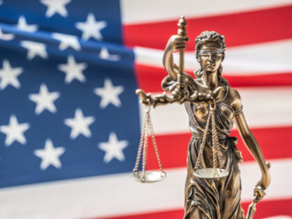 The statue of justice, goddess of justice in front of american flag.