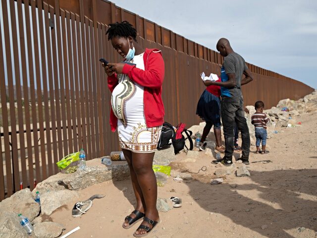 YUMA, ARIZONA - DECEMBER 07: An immigrant family from Haiti waits to be taken into custody at the U.S.-Mexico border on December 07, 2021 in Yuma, Arizona. In many cases migrant families with pregnant mothers are allowed by Mexican immigration officials to proceed to the U.S. border, where they can …