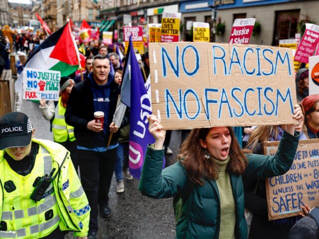 GLASGOW, SCOTLAND - MARCH 18: People carry placards as they march during a Stand Up To Racism protest at George Square on March 18, 2023 in Glasgow, Scotland. Given the rise of far-right protests and increased hostility towards people seeking protection, Just Stop Racism are standing in solidarity against hate …