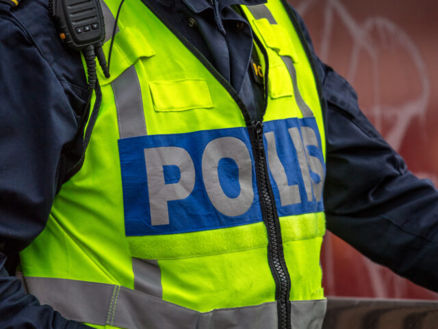 Close up of Swedish police officer wearing a luminous yellow green vest with police text. Only upper body visible, no recognizable person.