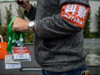 A Marshal holding badges which protesters participating in the March are required to wear by the police during a demonstration against Land Reclamation on March 26, 2023 in Hong Kong, China. Today residents held a demonstration against a proposed land reclamation plan by the government, organizers say that 80 people …