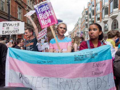 LONDON, UNITED KINGDOM - 2021/06/26: Protestors seen with a banner that says 'protect trans kids!' and placards demanding 'trans rights now' during the march.