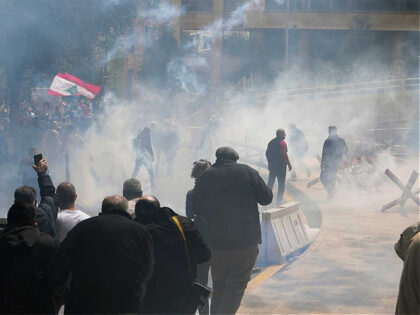 Retired members of the Lebanese security and other protesters run amid tear gas fired by r