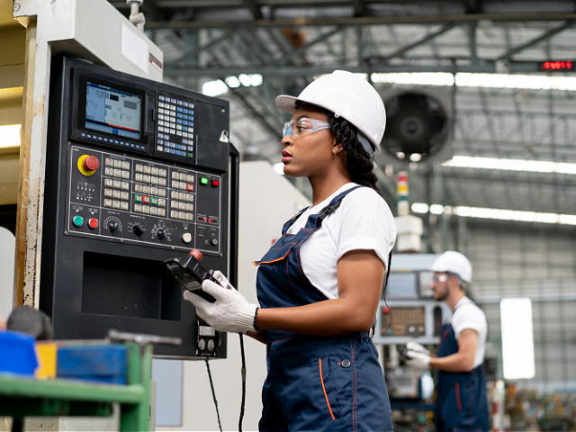 Technician woman inspecting CNC machines controlled manufacturing with computer industrial - stock photo