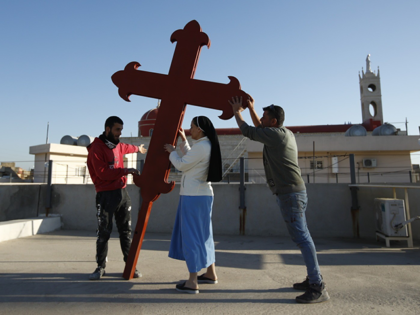 Iraqi Christians place a cross on a church in Qaraqosh, Iraq, Monday, Feb. 22, 2021. Iraq&