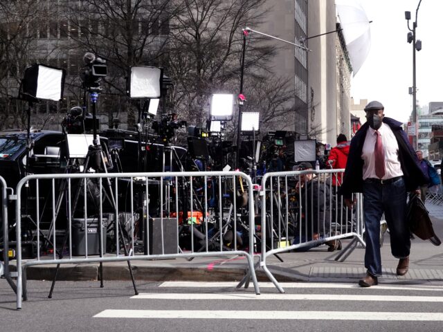 NEW YORK, NEW YORK - MARCH 22: People walk by journalists reporting outside of the Criminal Courts Building as the grand jury continues to hear evidence against former President Donald Trump on March 22, 2023 in New York City. The grand jury is meeting to decide if Trump should be …