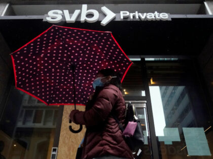 A pedestrian carries an umbrella while walking past a Silicon Valley Bank Private branch i