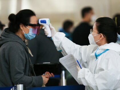 LOS ANGELES, CALIFORNIA - DECEMBER 22: A traveler receives a a temperature check before ch