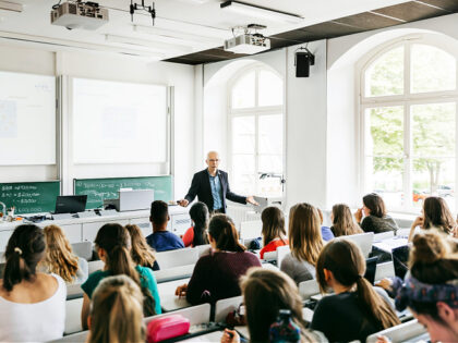 A university professor addressing his pupils during a lecture in a bright, modern lecture theatre. classroom