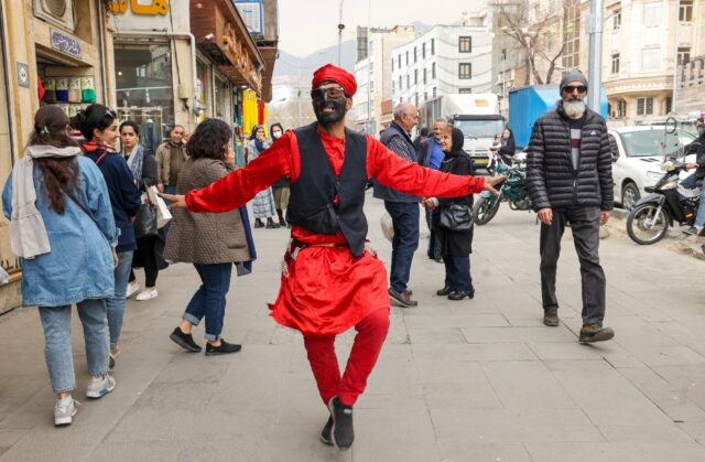 An Iranian man dressed as the fictional folklore character Hajji Firuz performs on at a st