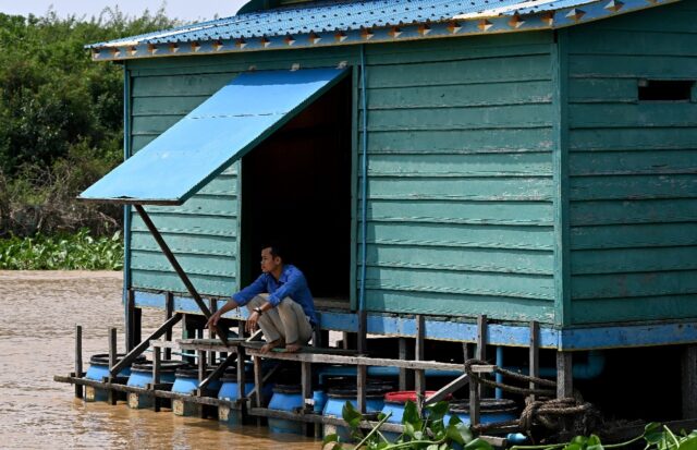 A teacher squats above floating toilets in Chong Prolay village on Cambodia's Tonle Sap la