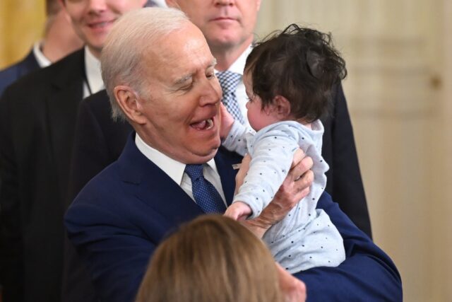 US President Joe Biden holds the baby son of a Democratic congressman at a speech on gover