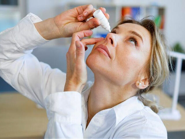 Business woman office worker dripping eye drops - stock photo
