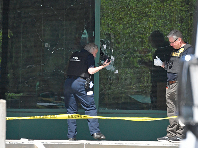 A Louisville Metro Police technician photographs bullet holes in the front glass of the Old National Bank building in Louisville, Ky., Monday, April 10, 2023. A shooting at the bank killed and wounded several people police said. The suspected shooter was also dead. (AP Photo/Timothy D. Easley)