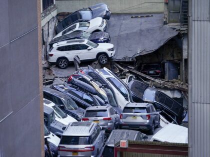 Cars are seen piled on top of each other at the scene of a partial collapse of a parking g