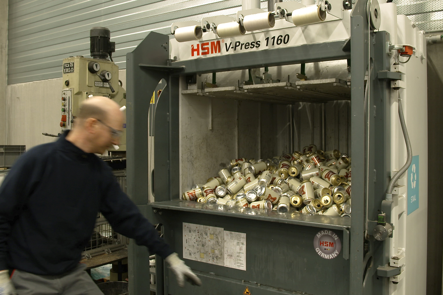 In this image provided by Comite Champagne, a worker prepares to press the button of a machine to crush empty Miller High Life beer cans at the Westlandia plant in Ypres, Belgium, Monday, April 17, 2023. Belgian customs have destroyed more than 2,000 cans of Miller High Life advertised as the ″Champagne of beers” at the request of houses and growers of the bubbly beverage. (Comite Champagne via AP)
